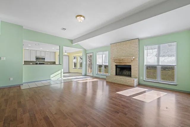 a view of empty room with wooden floor and fireplace