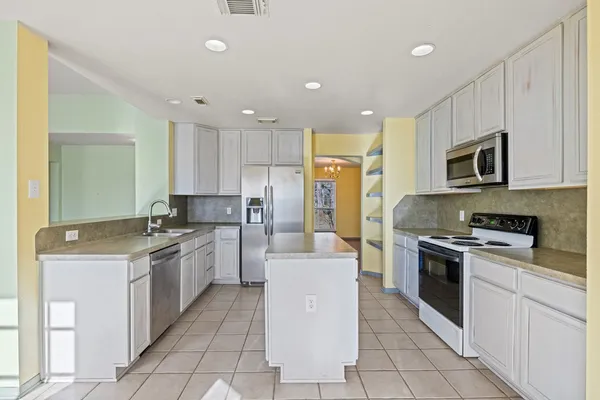 a large kitchen with stainless steel appliances lots of white cabinets