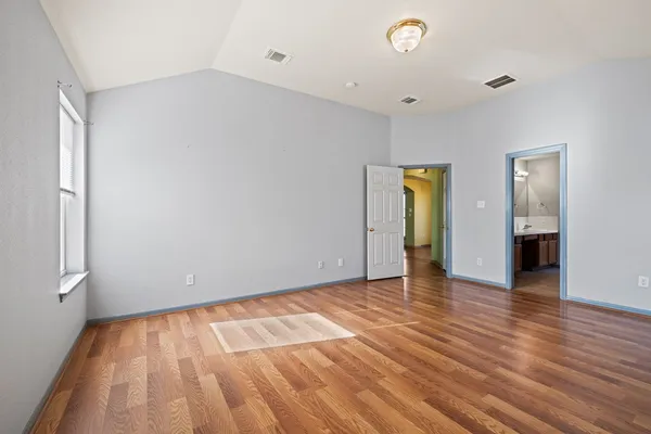 a view of an empty room with wooden floor and closet