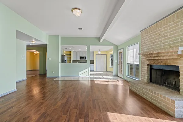 an empty room with wooden floor fireplace and windows