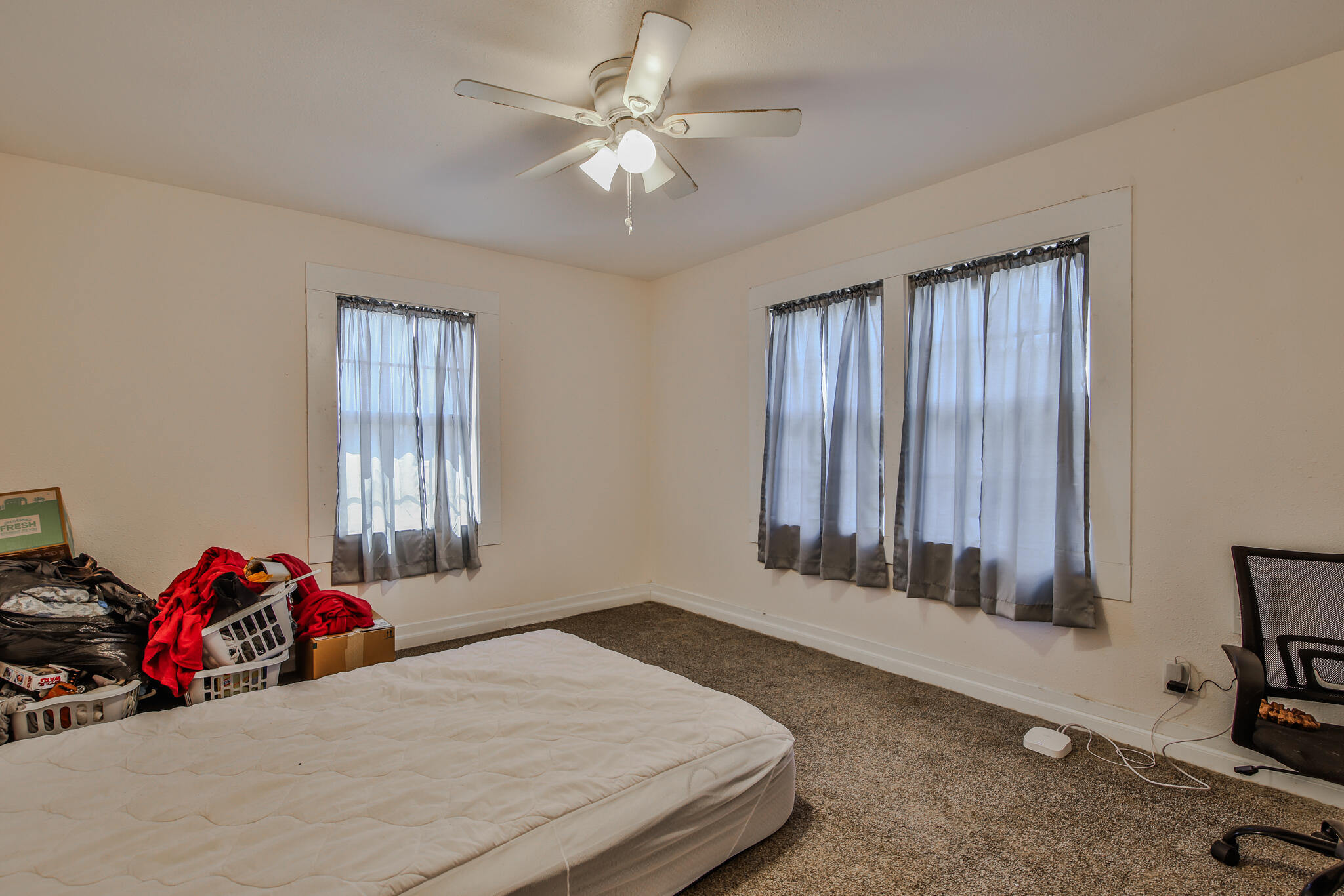 805 South 4th Street Slaton, TX 79364 - Photo 7 of 28 a bedroom with a bed a chandelier and a window
