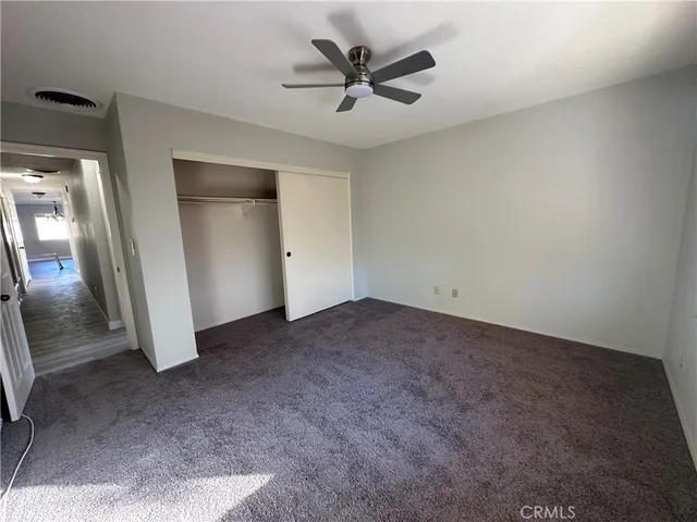an empty room with closet and a ceiling fan