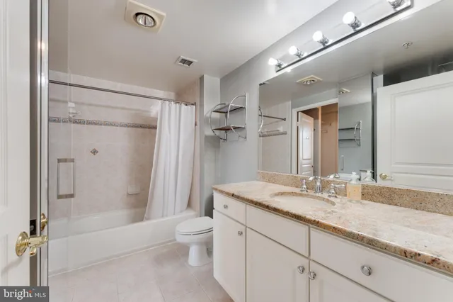 a bathroom with a granite countertop sink a toilet and shower