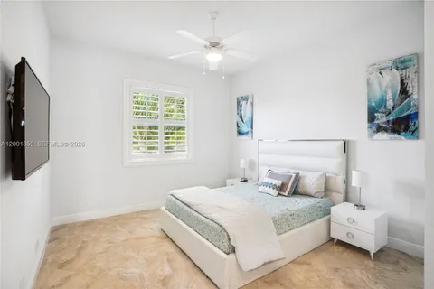 a bedroom with a bed a flat screen tv and a window