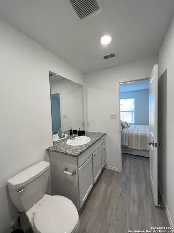 a en suite bathroom with a granite countertop toilet sink and mirror
