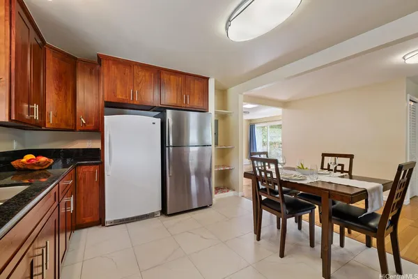 a kitchen with stainless steel appliances granite countertop a refrigerator a stove a sink a dining table and chairs with wooden floor