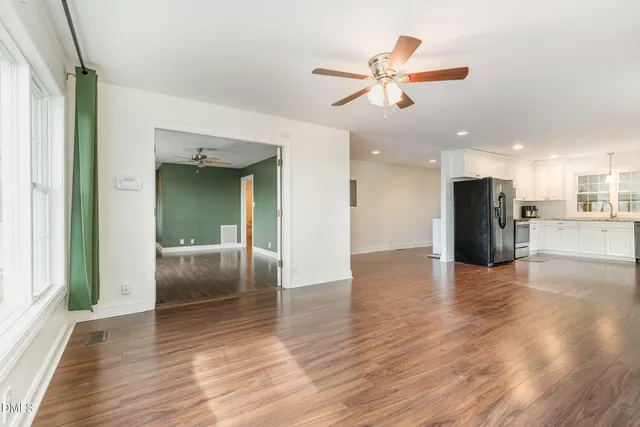 a kitchen with stainless steel appliances granite countertop a stove top oven a sink dishwasher and white cabinets with wooden floor