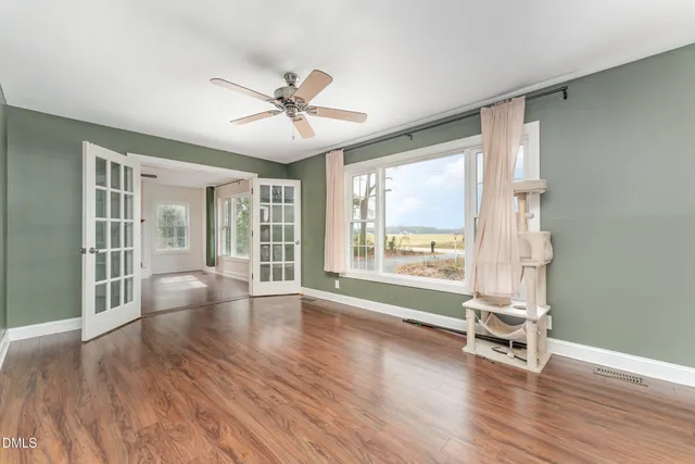 an empty room with wooden floor window and ceiling fan