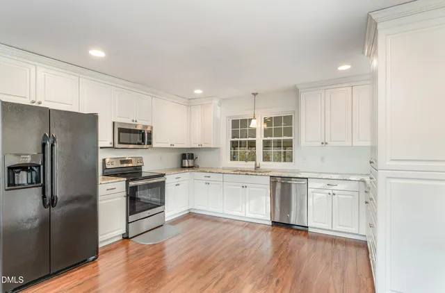 a view of an empty room with wooden floor and a ceiling fan