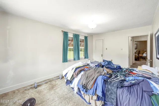 a bed sitting in a bedroom next to a window and dresser