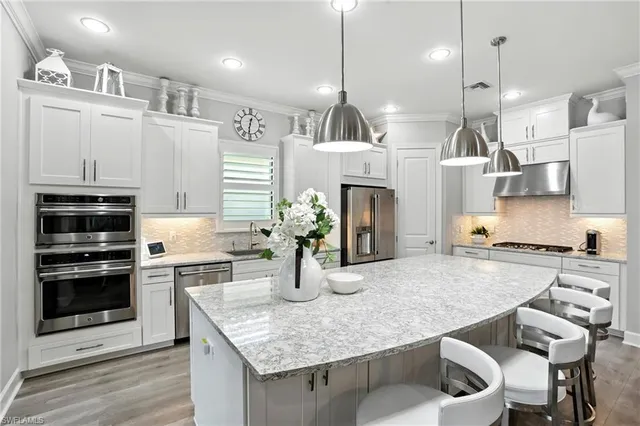 a kitchen with kitchen island a stove a sink a oven and a refrigerator