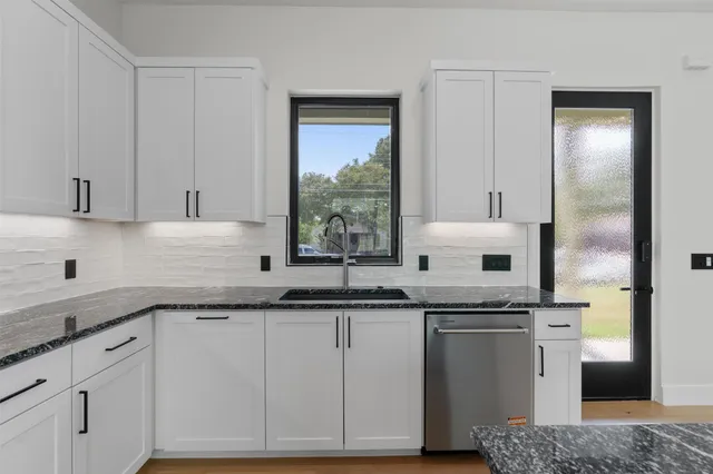 a kitchen with stainless steel appliances granite countertop a sink and a white cabinets