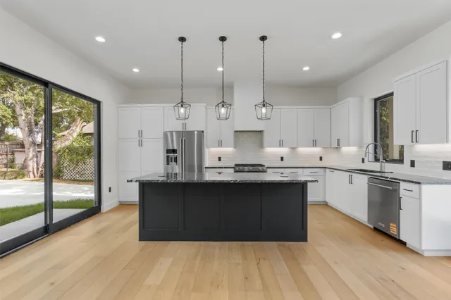 a kitchen with stainless steel appliances granite countertop a sink a stove and a refrigerator