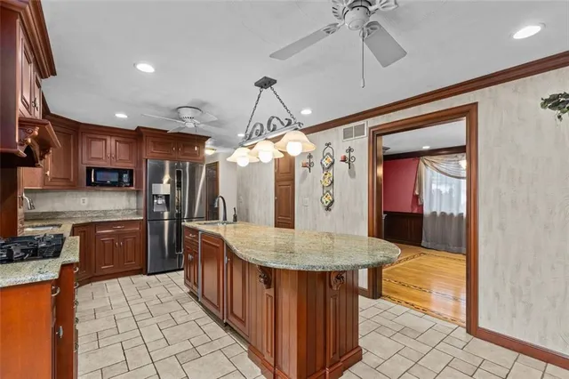 a kitchen with stainless steel appliances granite countertop a sink a stove and a wooden cabinets