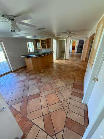 328 Heather Ridge Circle Sandy, UT 84070 - Photo 23 of 32 Spacious common area featuring patterned terracotta-style floor tiling, a built-in bar with dark countertop and wood-finish cabinetry, and multiple ceiling fans