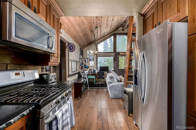 a kitchen with stainless steel appliances granite countertop a refrigerator stove and a sink with wooden floor