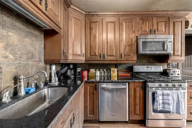 a kitchen with stainless steel appliances granite countertop a stove a sink and a microwave