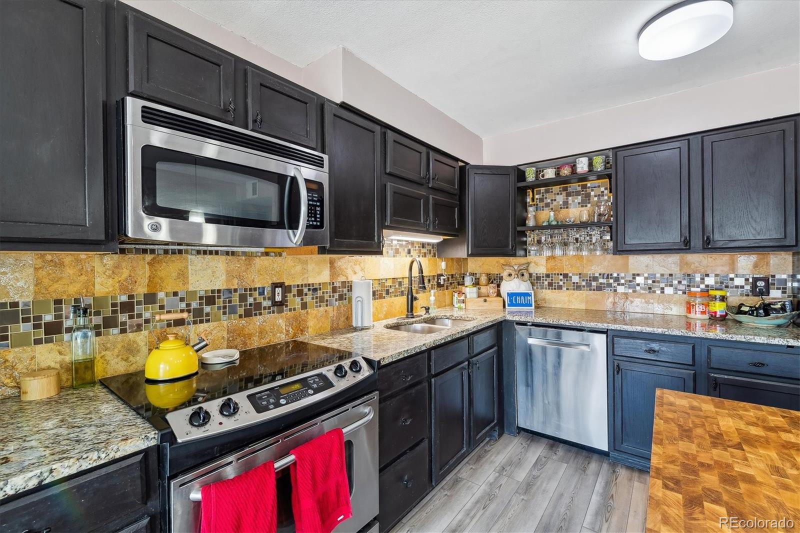 6495 East Happy Canyon Road, Unit 163 Denver, CO 80237 - Photo 4 of 27 a kitchen with stainless steel appliances granite countertop a stove a sink dishwasher and a microwave oven with wooden floor