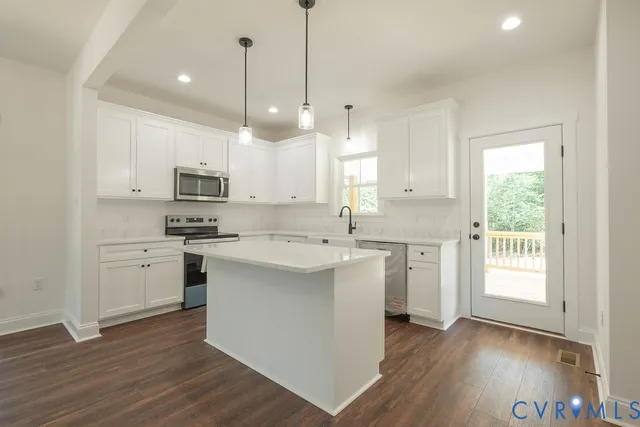 a kitchen with kitchen island granite countertop a sink cabinets and wooden floor