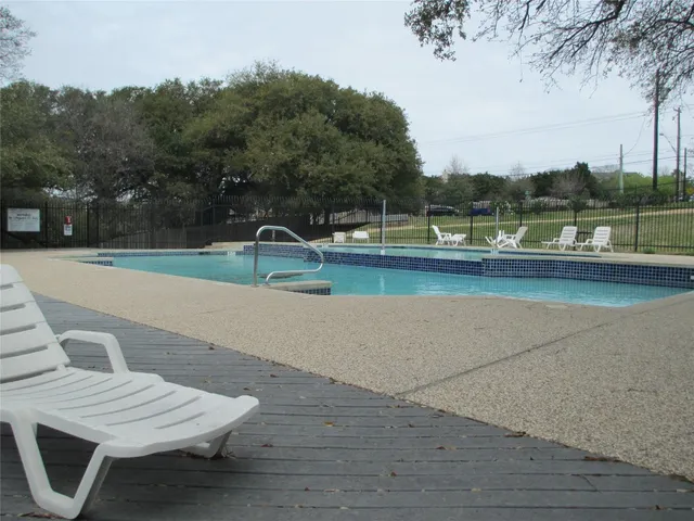 a view of swimming pool with lounge chair and trees