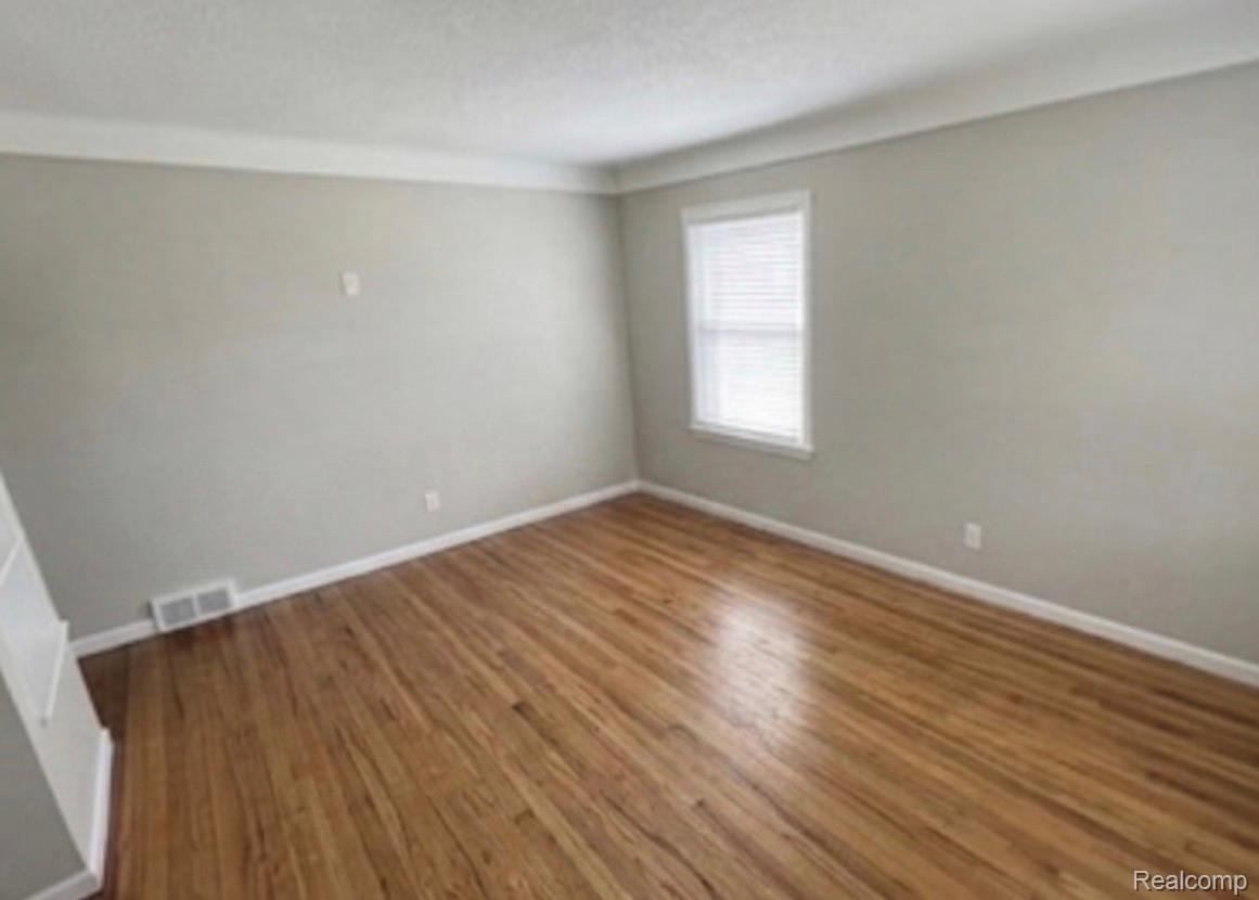 Empty room featuring baseboards and dark wood-style floors