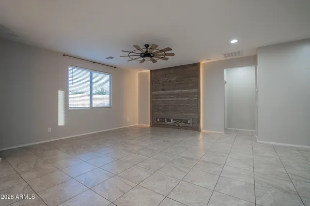 an empty room with staircase and a ceiling fan