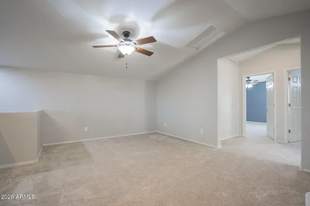 an empty room with a chandelier fan and windows