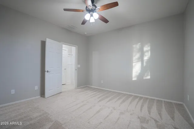 an empty room with windows and fan