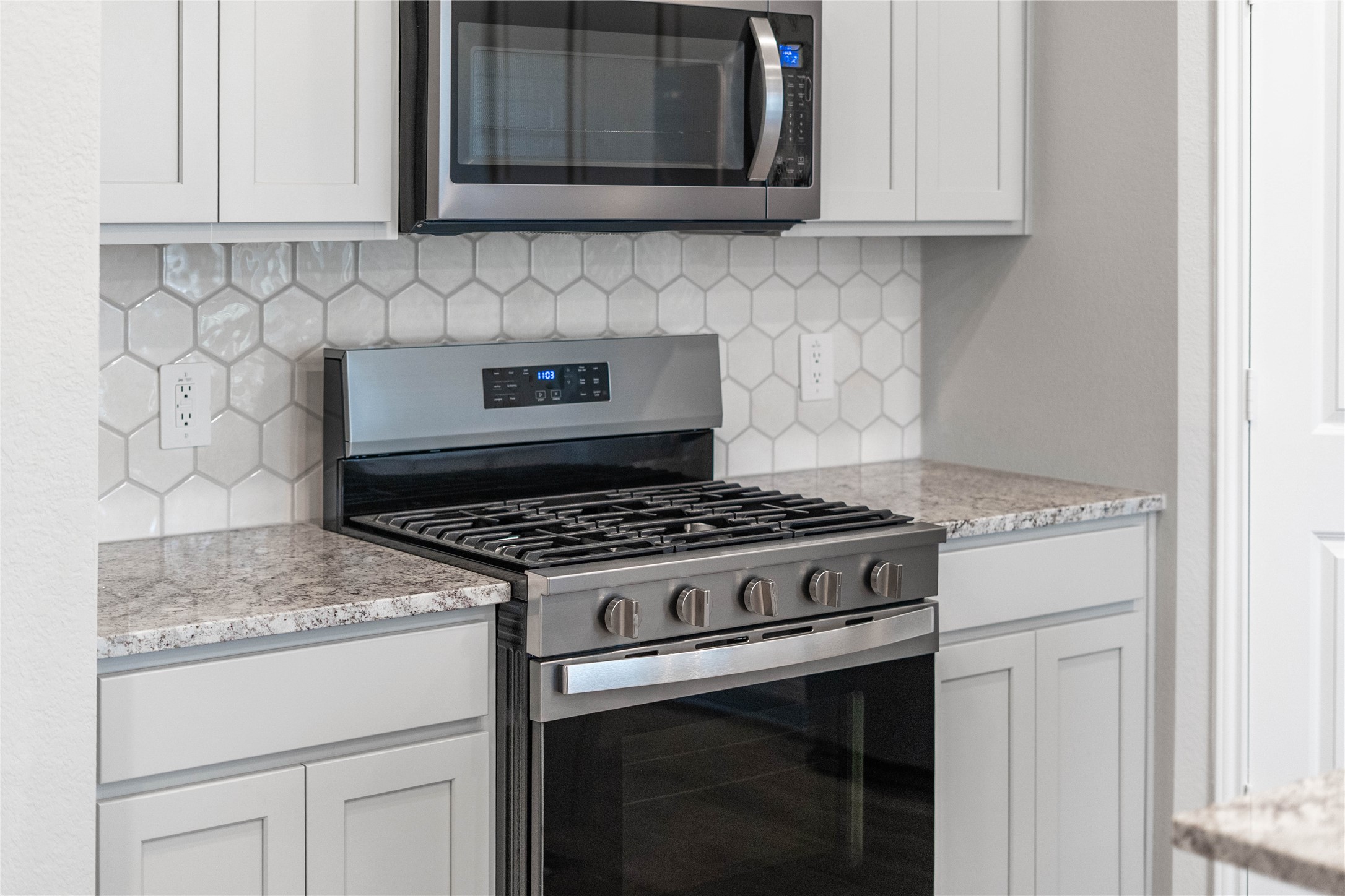 19645 Montgomery Rdg Way Montgomery, TX 77316 - Photo 14 of 41 Showcased here is a Whirlpool gas range, paired with a steam microwave equipped with sensor cooking—all framed by an elegant tile backsplash.
