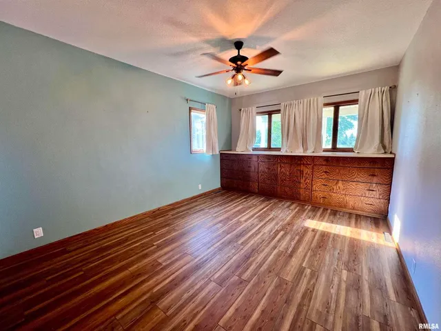 an empty room with windows and fan