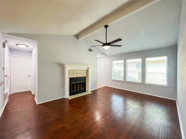 an empty room with wooden floor fireplace and windows