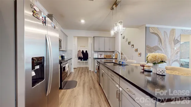 a kitchen with stainless steel appliances granite countertop a refrigerator a stove and a wooden floor