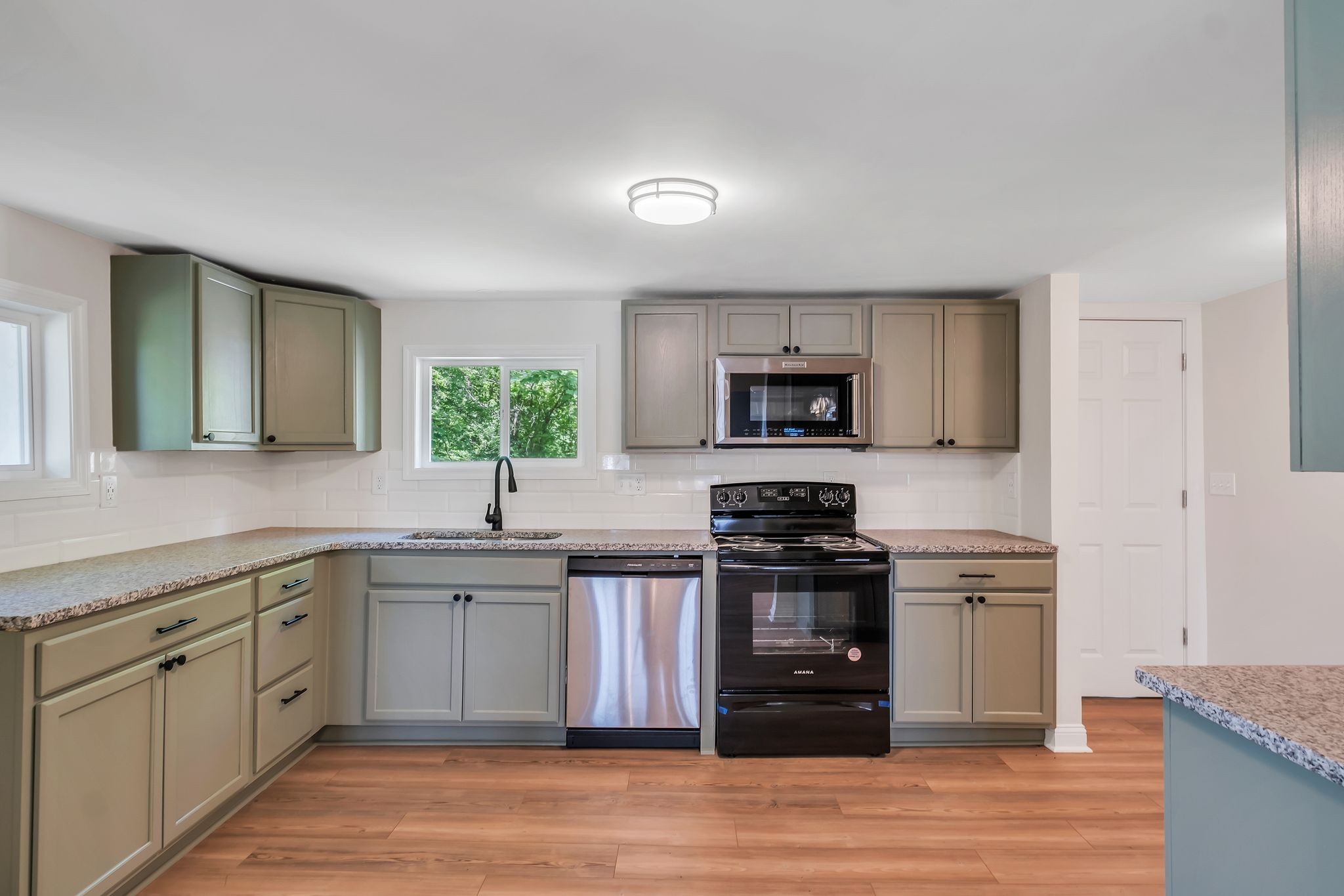 a kitchen with stainless steel appliances granite countertop a stove top oven a sink and dishwasher with wooden floor