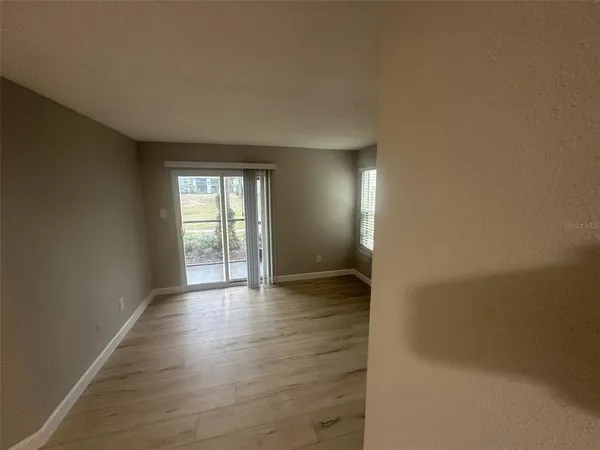 a view of an empty room with wooden floor and a window
