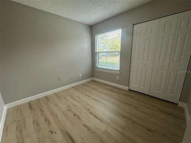 an empty room with wooden floor and windows with curtains