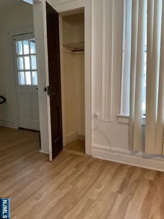 an empty room with wooden floor closet and windows