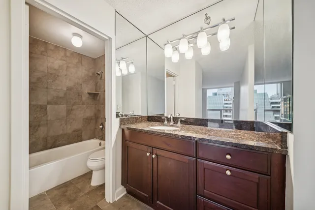 a bathroom with a granite countertop sink a toilet and bathtub