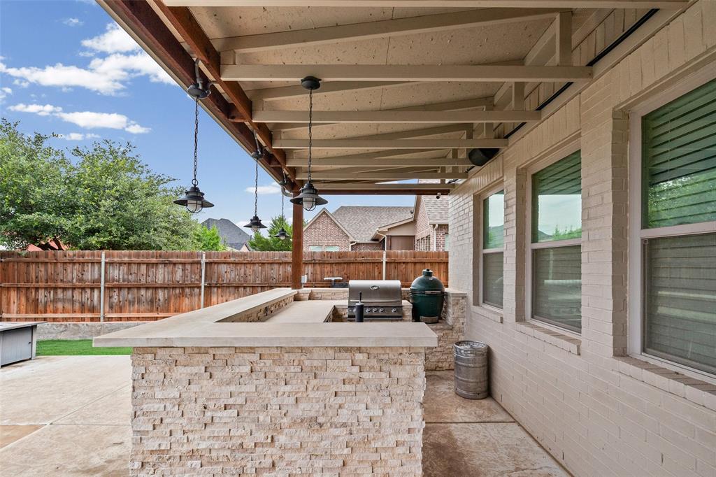 437 Prairie Run Aledo, TX 76008 - Photo 30 of 33 Outdoor kitchen featuring a stone veneer island with countertop, built-in grill, and covered patio with exposed beam ceiling
