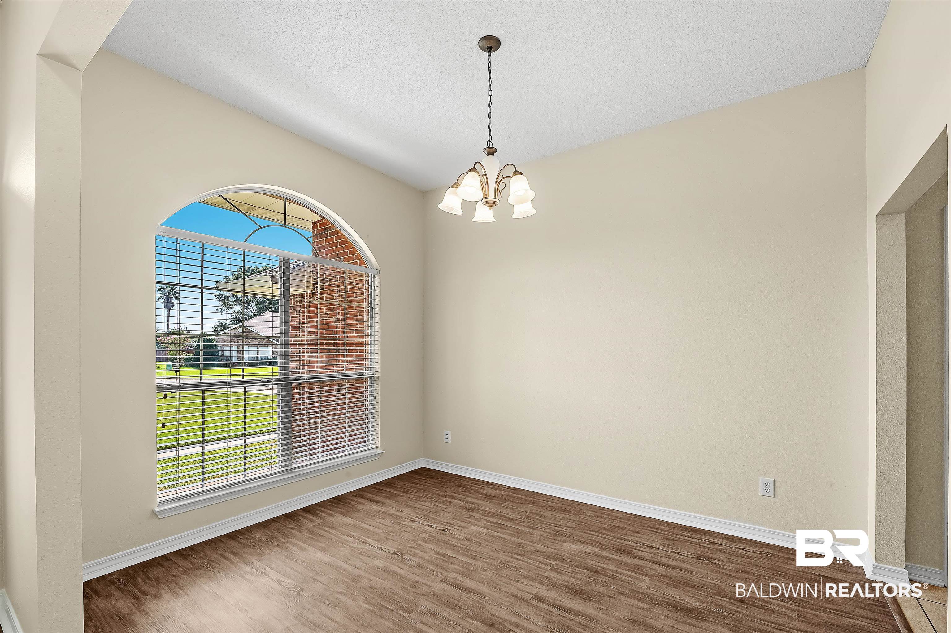12443 Venice Boulevard Foley, AL 36535 - Photo 14 of 59 Spare room with a textured ceiling, dark wood-type flooring, a chandelier, and lofted ceiling