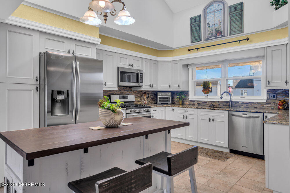 2111 Middle Avenue Point Pleasant, NJ 08742 - Photo 14 of 51 a kitchen with stainless steel appliances granite countertop a sink a stove a refrigerator a microwave a dining table and chairs