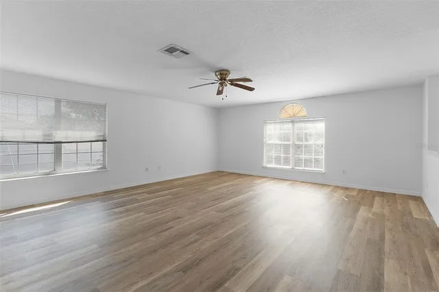 an empty room with wooden floor and windows