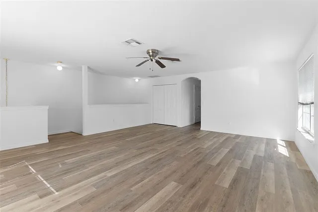 a view of empty room with wooden floor and fan