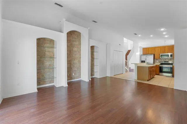 a view of a living room with wooden floor and a kitchen