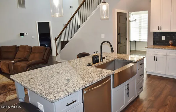 a kitchen with granite countertop a sink a counter top space and cabinets