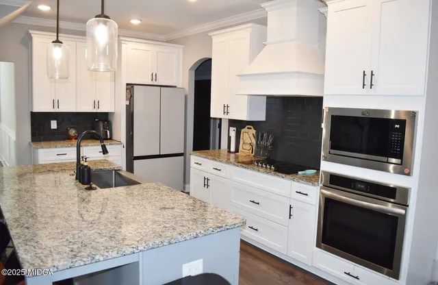 a kitchen with stainless steel appliances kitchen island granite countertop a stove microwave and refrigerator