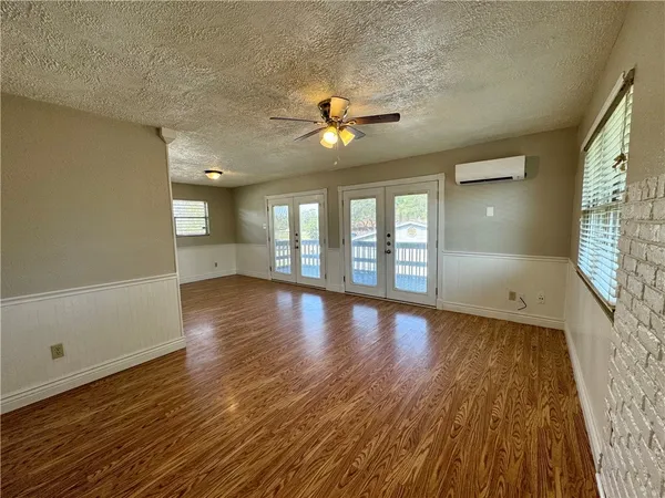 a view of an empty room with window and wooden floor