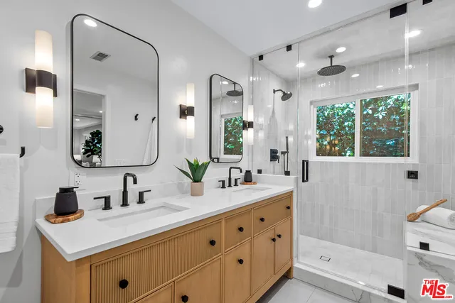 a bathroom with a double vanity sink mirror and shower