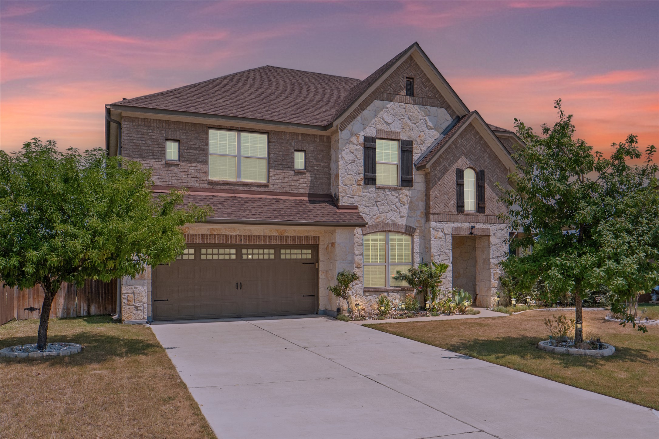 This two-story home boasts a striking blend of stone and brick exterior with rustic wood shutters, and a welcoming covered porch.