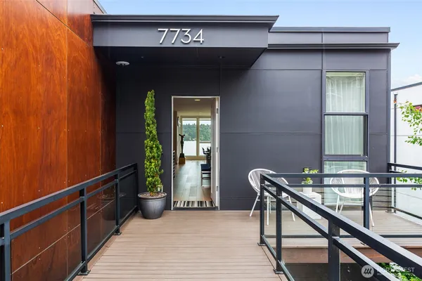 a living room with furniture a rug kitchen view and large windows