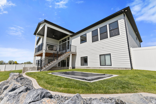 3111 South 1250 West Logan, UT 84321 - Photo 41 of 51 Contemporary exterior featuring white siding with black trim, a covered upper-level deck, a lower-level patio, and a fully fenced yard